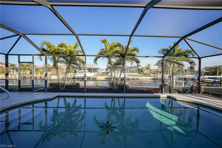 View of pool featuring a water view and glass enclosure