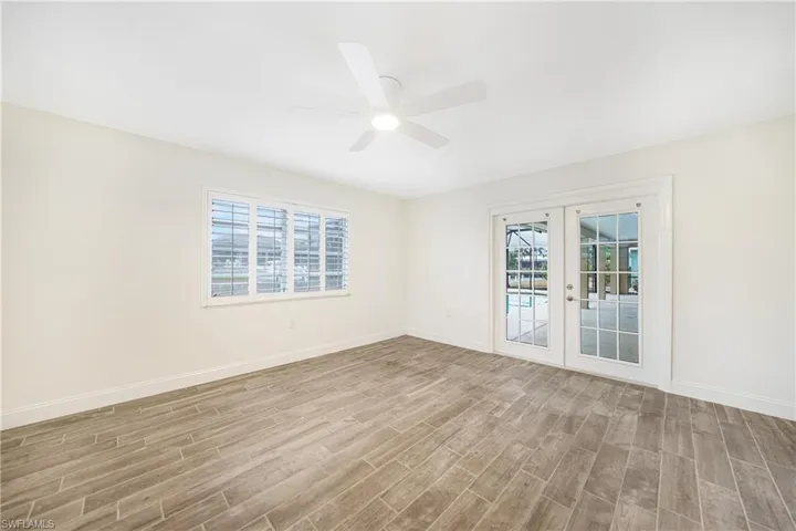 Unfurnished room with a healthy amount of sunlight, light hardwood / wood-style flooring, ceiling fan, and french doors