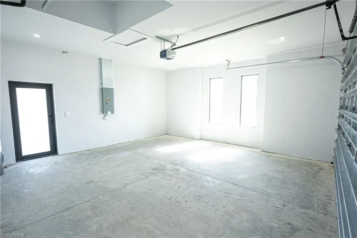 Garage featuring recessed lighting, a garage door opener, and electric panel
