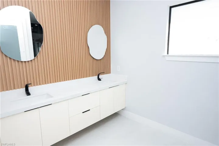 Bathroom featuring wood walls, double vanity, a sink, and baseboards