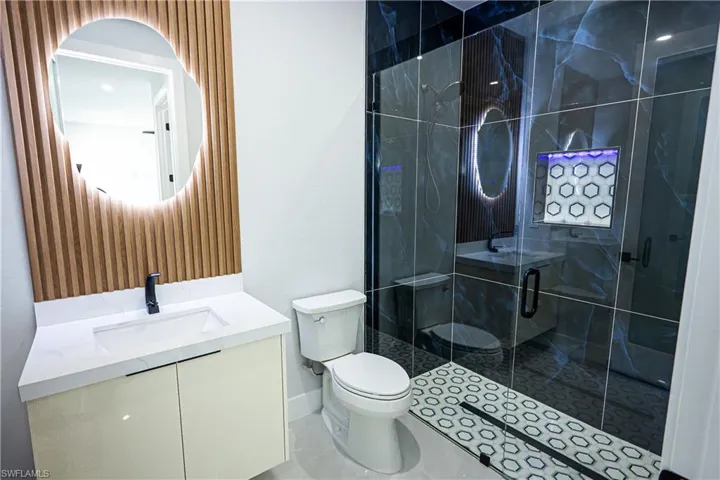 Bathroom with toilet, a stall shower, and vanity