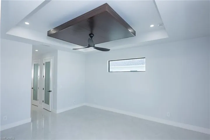 Unfurnished room featuring a tray ceiling, baseboards, a ceiling fan, and recessed lighting