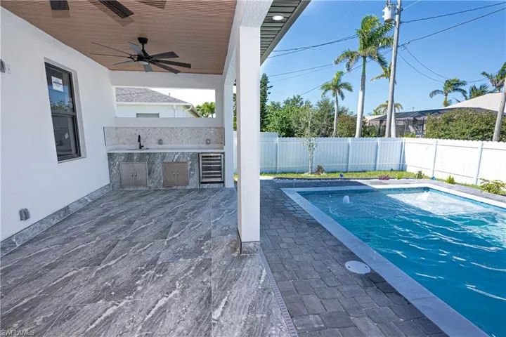View of swimming pool with a patio area, a fenced backyard, exterior kitchen, and a ceiling fan