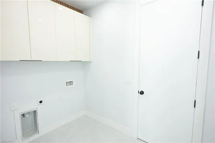 Washroom with electric dryer hookup, baseboards, hookup for a washing machine, and cabinet space