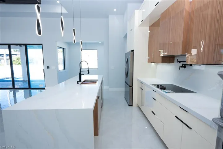 Kitchen featuring freestanding refrigerator, modern cabinets, white cabinets, a sink, and black electric stovetop