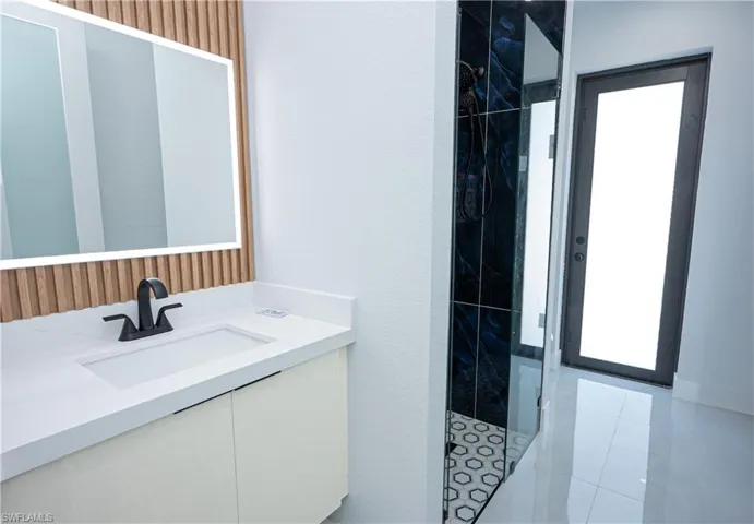 Full bath with tile patterned flooring, vanity, and a stall shower