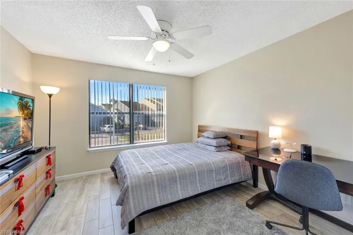 Bedroom with ceiling fan, a textured ceiling, and light wood-style tile floors