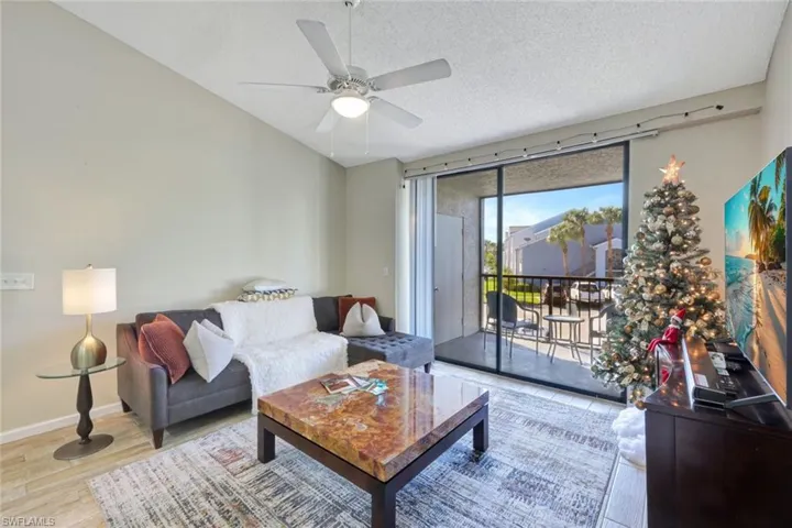 Living room with vaulted ceiling, light wood-style tile floors, and ceiling fan