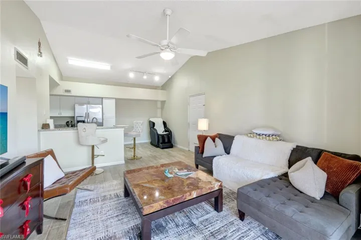 Living room with ceiling fan, vaulted ceiling, and light wood-style tile floors