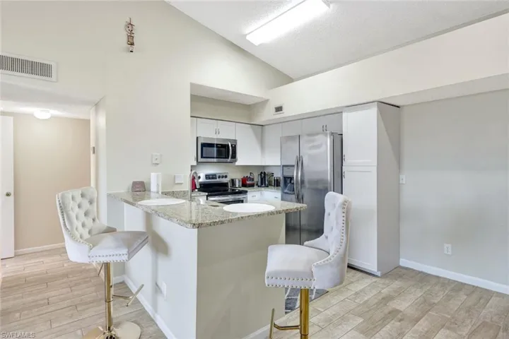 Kitchen featuring kitchen peninsula, a breakfast bar, light wood-style tile floors, and appliances with stainless steel finishes