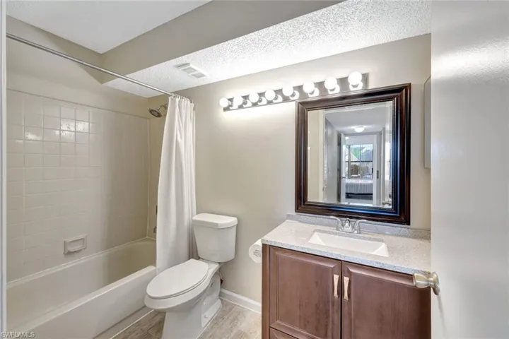 Full bathroom featuring vanity, toilet, light wood-style tile floors, and shower / tub combo