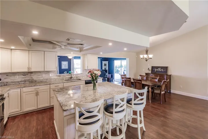 Kitchen with backsplash, dark hardwood / wood-style floors, a raised ceiling, and sink