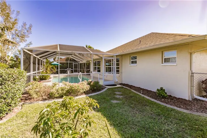 Rear view of property with a lawn and a lanai
