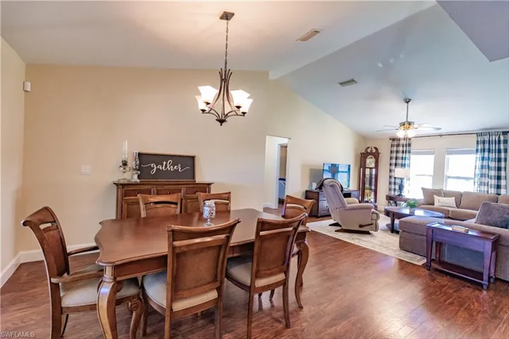 Dining area with ceiling fan with notable chandelier, lofted ceiling, and dark wood-type flooring