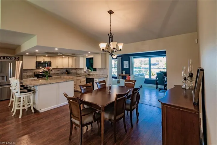 Dining room featuring dark hardwood / wood-style floors, high vaulted ceiling, and a chandelier