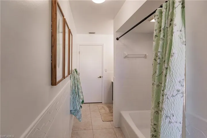 Bathroom featuring shower / tub combo with curtain and tile patterned flooring