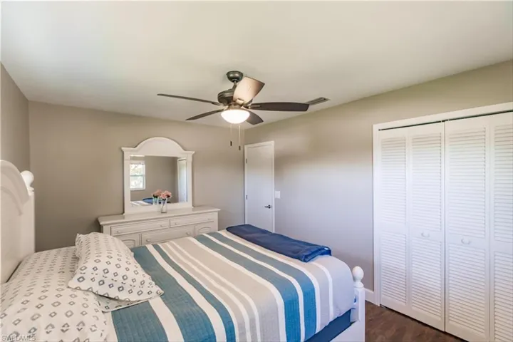Bedroom with a closet, dark hardwood / wood-style floors, and ceiling fan