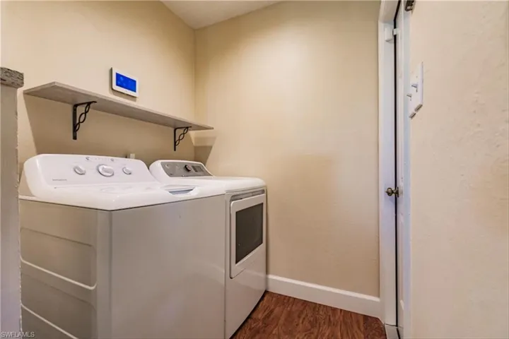 Washroom with washer and dryer and dark hardwood / wood-style floors