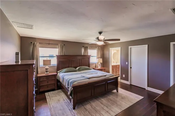 Bedroom with ceiling fan, dark hardwood / wood-style flooring, and connected bathroom