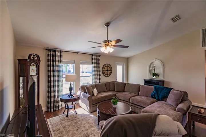 Living room featuring ceiling fan and dark wood-type flooring