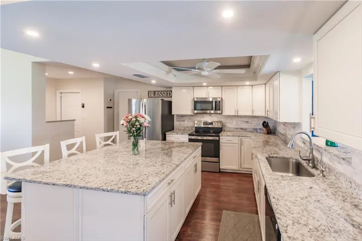Kitchen featuring a kitchen bar, appliances with stainless steel finishes, a kitchen island, and sink