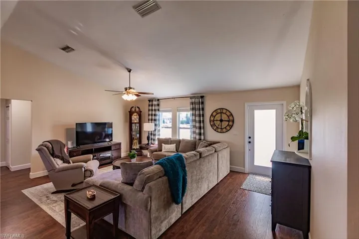Living room featuring ceiling fan, dark wood-type flooring, and vaulted ceiling