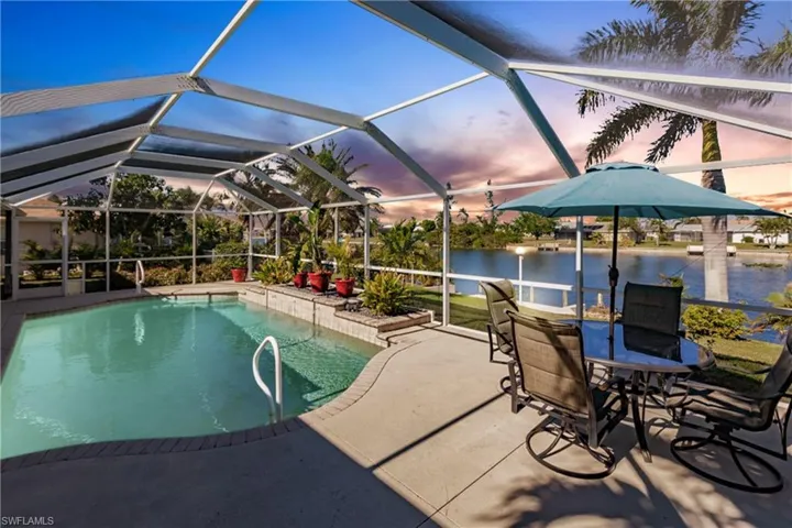 Pool at dusk with a water view, a lanai, and a patio area