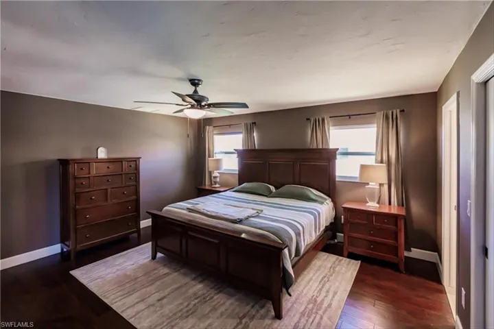Bedroom featuring multiple windows, dark wood-type flooring, and ceiling fan