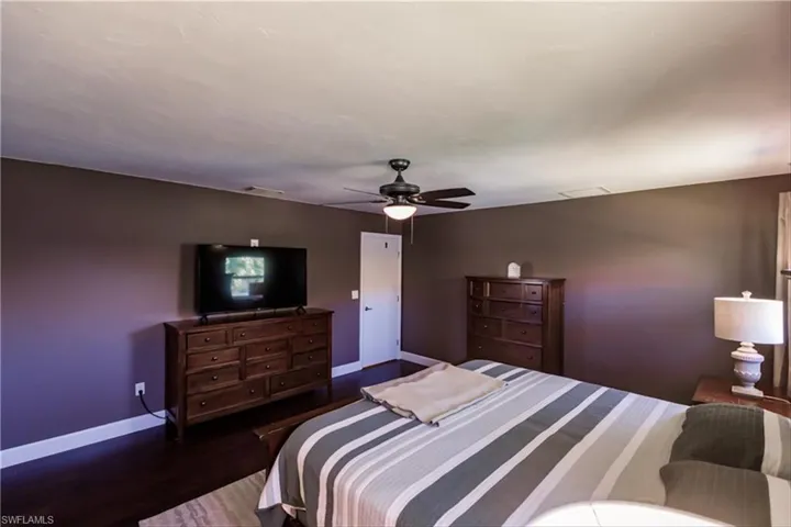Bedroom with ceiling fan and dark wood-type flooring