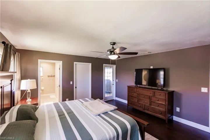 Bedroom featuring connected bathroom, ceiling fan, and dark wood-type flooring