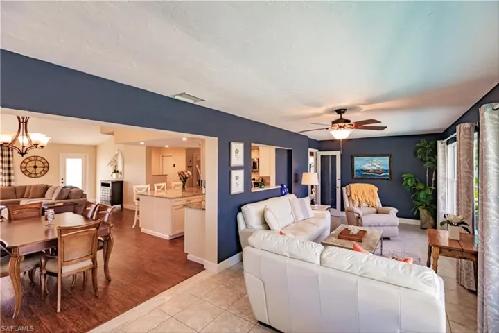 Living room featuring ceiling fan with notable chandelier and light wood-type flooring