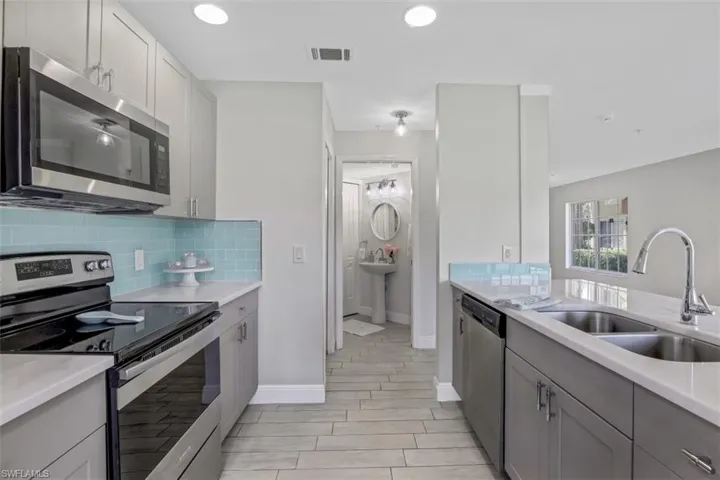 Kitchen featuring tasteful backsplash, stainless steel appliances, gray cabinetry, a sink, and visible vents
