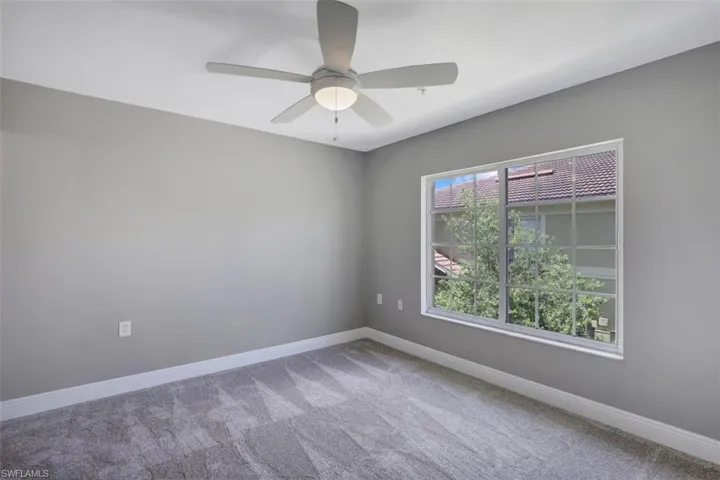 Carpeted empty room featuring baseboards and a ceiling fan
