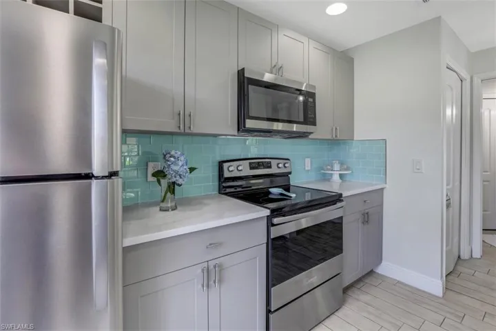 Kitchen with light countertops, tasteful backsplash, appliances with stainless steel finishes, and gray cabinetry