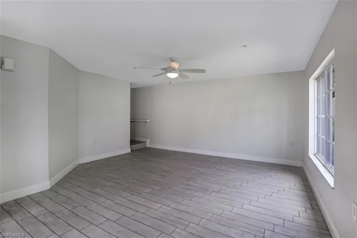 Empty room featuring wood finished floors, baseboards, and ceiling fan