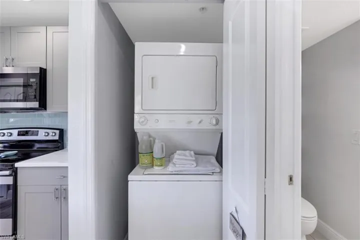 Clothes washing area featuring baseboards, stacked washing maching and dryer, and laundry area