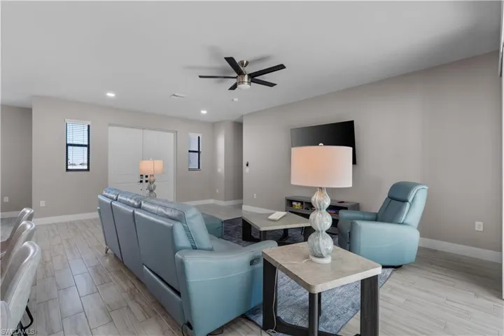 Living room featuring ceiling fan, wood finish floors, recessed lighting, and a glass covered fireplace