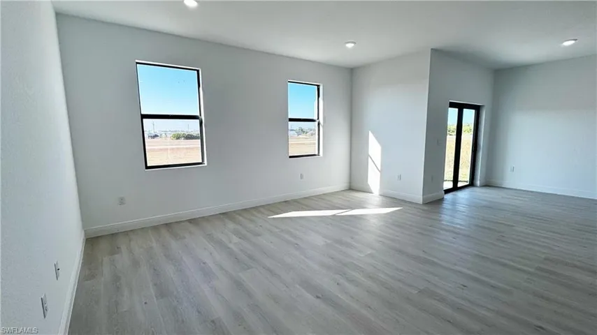 Spacious interior room featuring light wood-finish flooring and crisp white walls