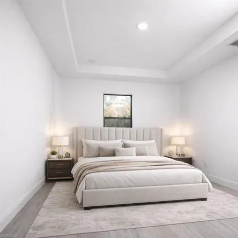 Spacious bedroom featuring a tray ceiling with recessed lighting, a square window, wood-finish flooring, and white baseboards