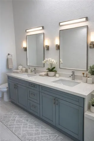 Double vanity featuring two rectangular undermount sinks, a light-toned countertop, and dual wall-mounted mirrors