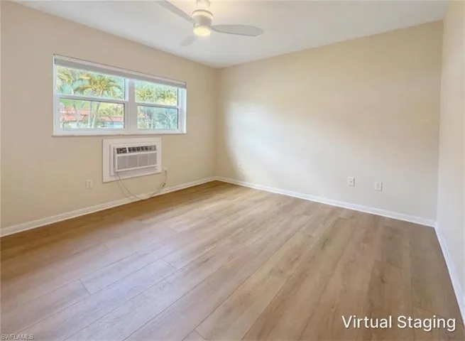 Room featuring wood-finish flooring, neutral wall paint, a multi-pane window, and a ceiling fan with integrated lighting