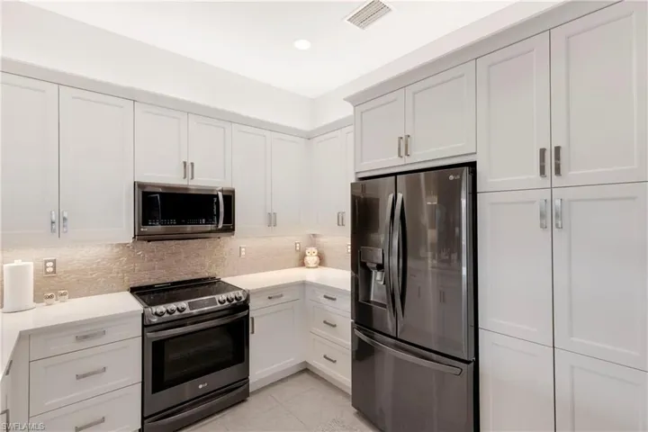 Kitchen featuring white cabinetry, appliances with stainless steel finishes, and decorative backsplash