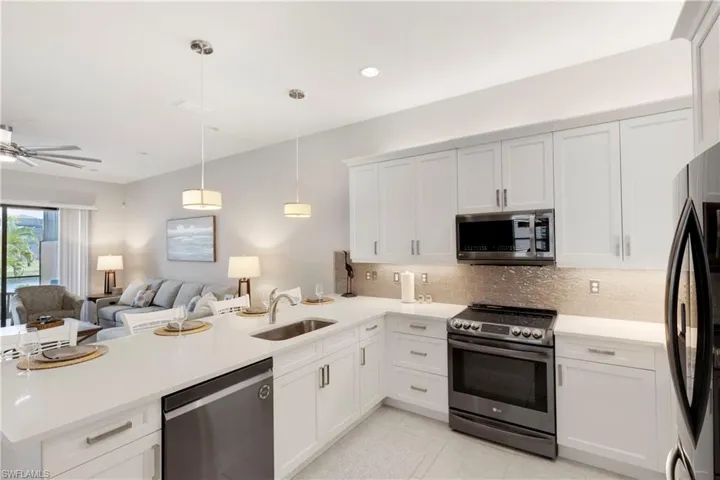 Kitchen featuring pendant lighting, sink, stainless steel appliances, decorative backsplash, and kitchen peninsula