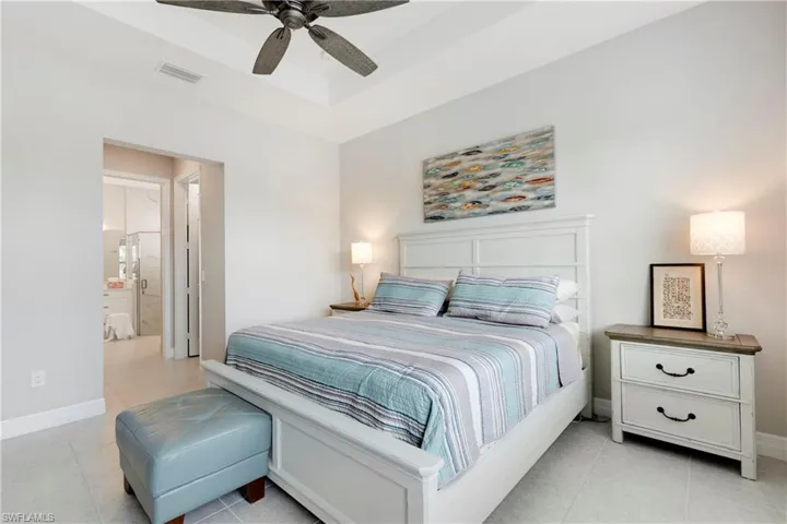 Bedroom with connected bathroom, ceiling fan, and light tile patterned floors