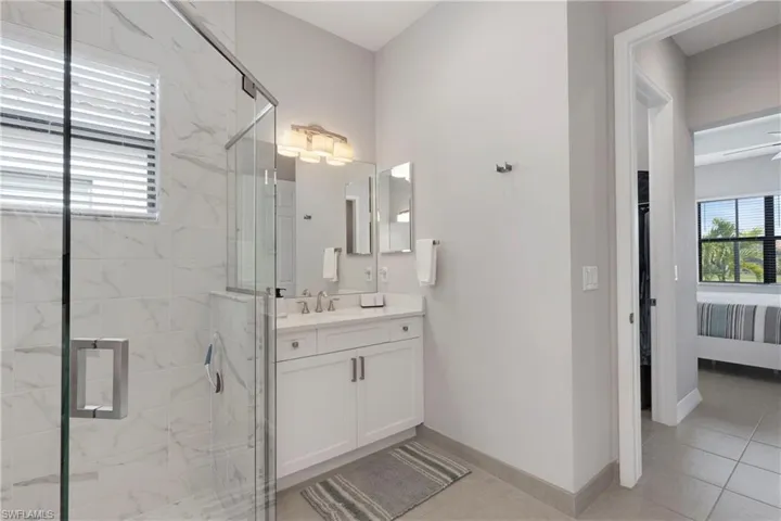 Bathroom with vanity, a shower with shower door, and tile patterned floors