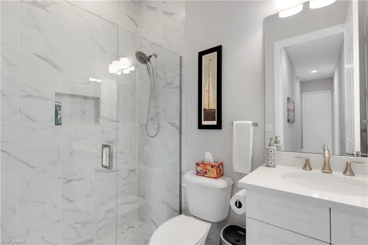 Bathroom featuring toilet, vanity, and walk in shower