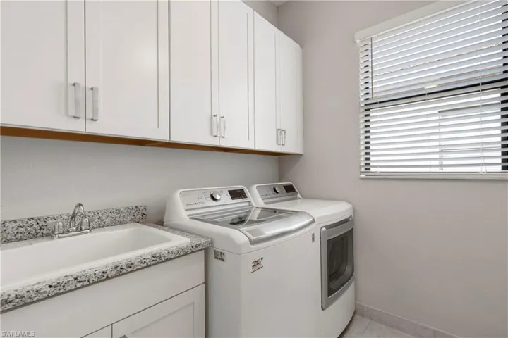 Washroom featuring cabinets, separate washer and dryer, sink, and light tile patterned floors