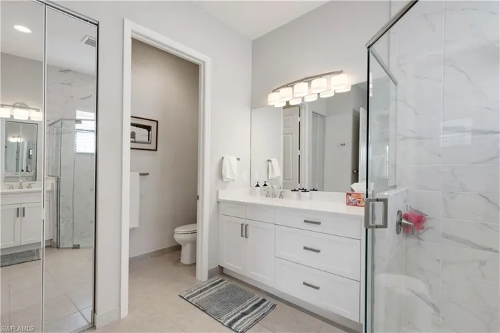 Bathroom featuring tile patterned floors, vanity, toilet, and an enclosed shower