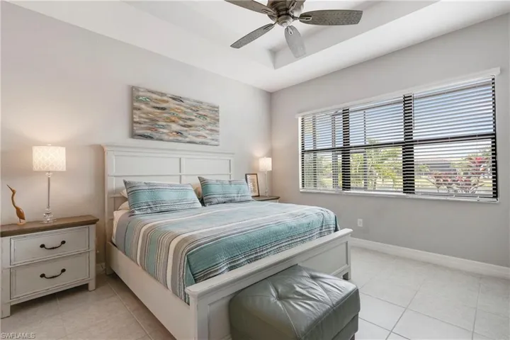 Tiled bedroom featuring a tray ceiling and ceiling fan