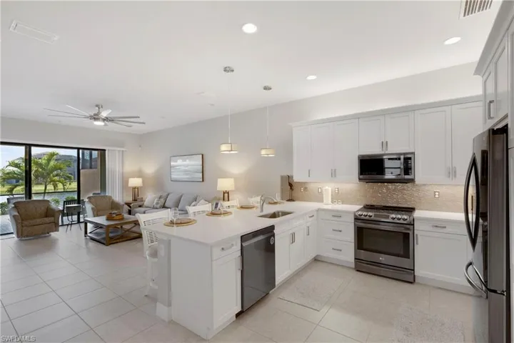 Kitchen with sink, kitchen peninsula, pendant lighting, stainless steel appliances, and white cabinets
